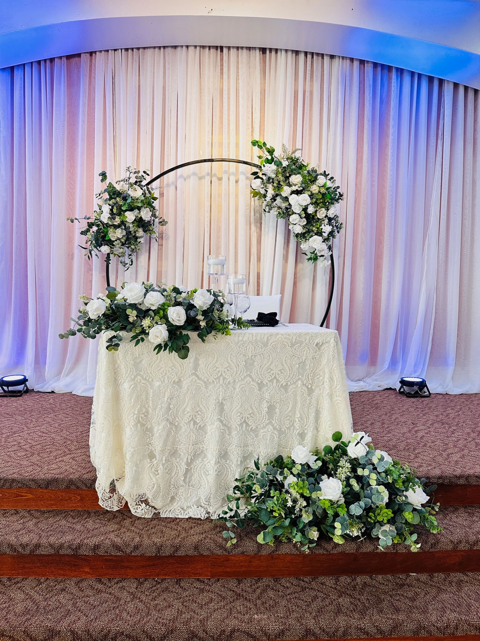 there is a sweetheart table with flowers on it in front of a curtain .