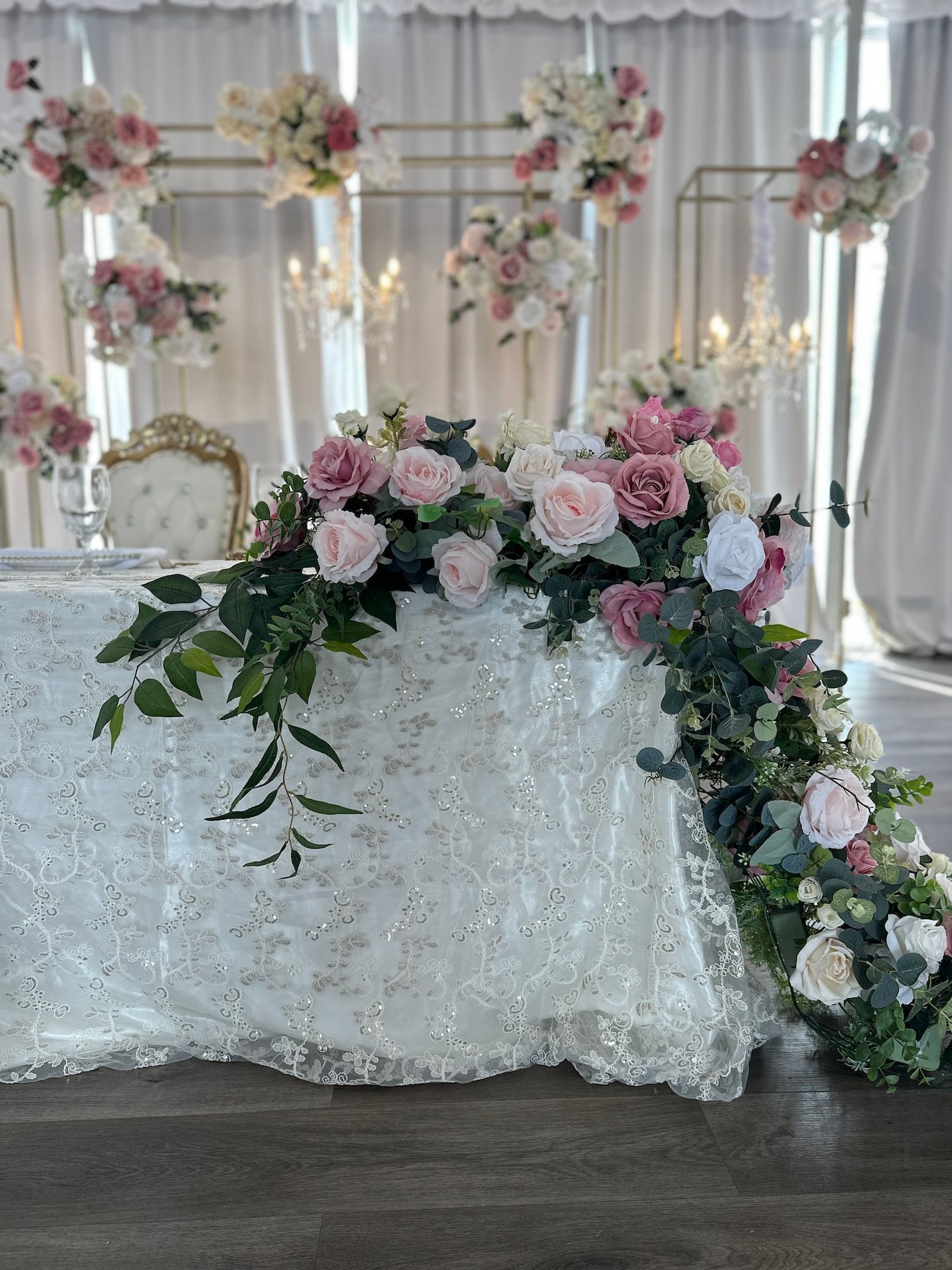 a sweetheart table with a white table cloth and flowers on it .