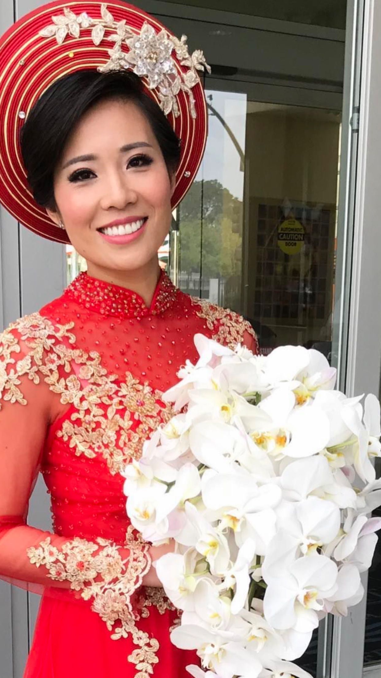 A woman in a red dress is holding a bouquet of white flowers.