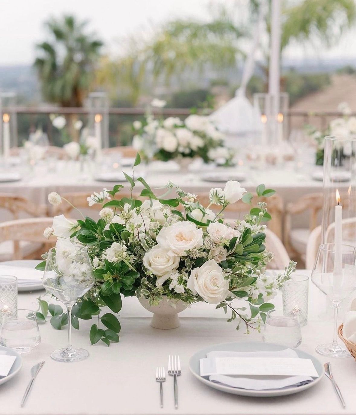 A table set for a wedding reception with white flowers in a vase on it.