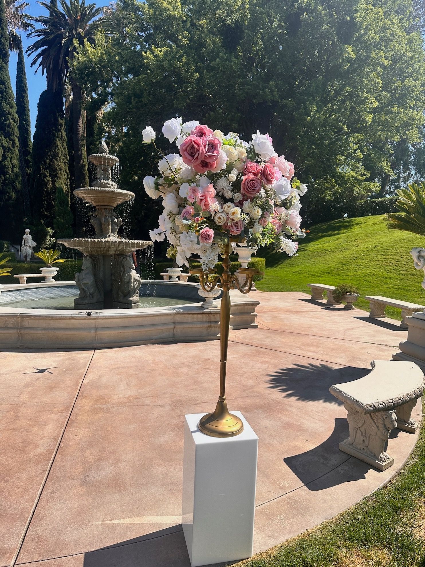 a candelabra with pink and white flowers in front of a fountain
