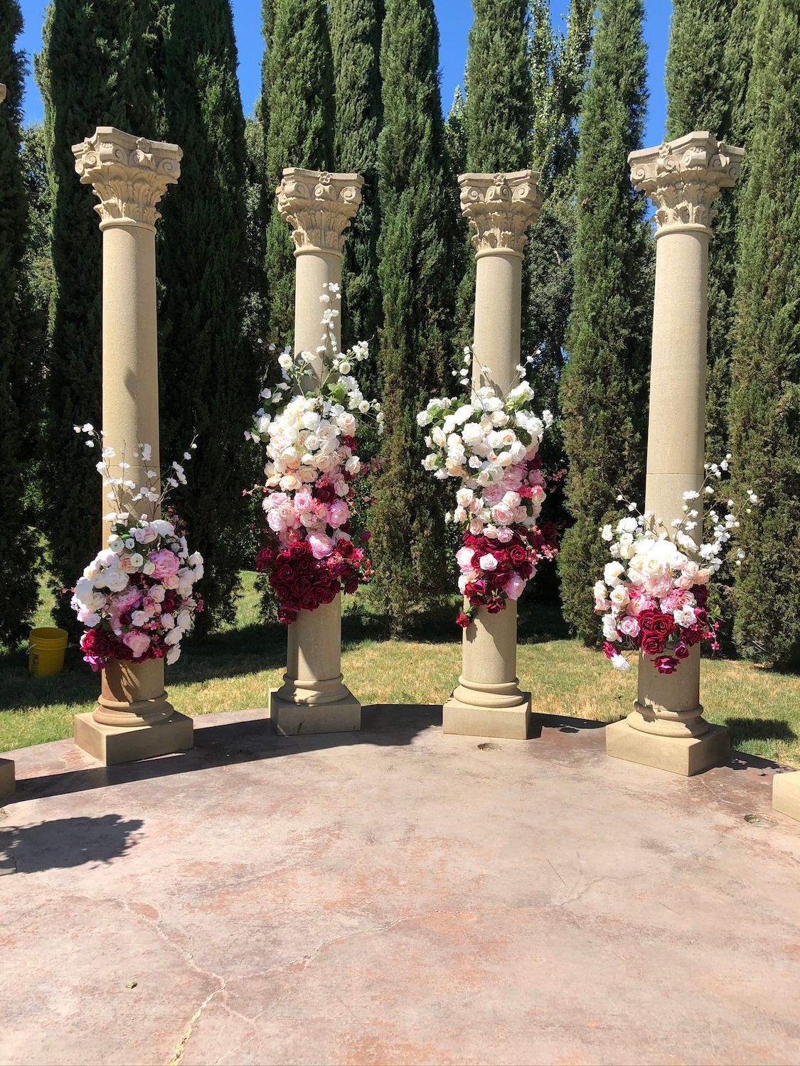 Three columns are decorated with flowers in a park.