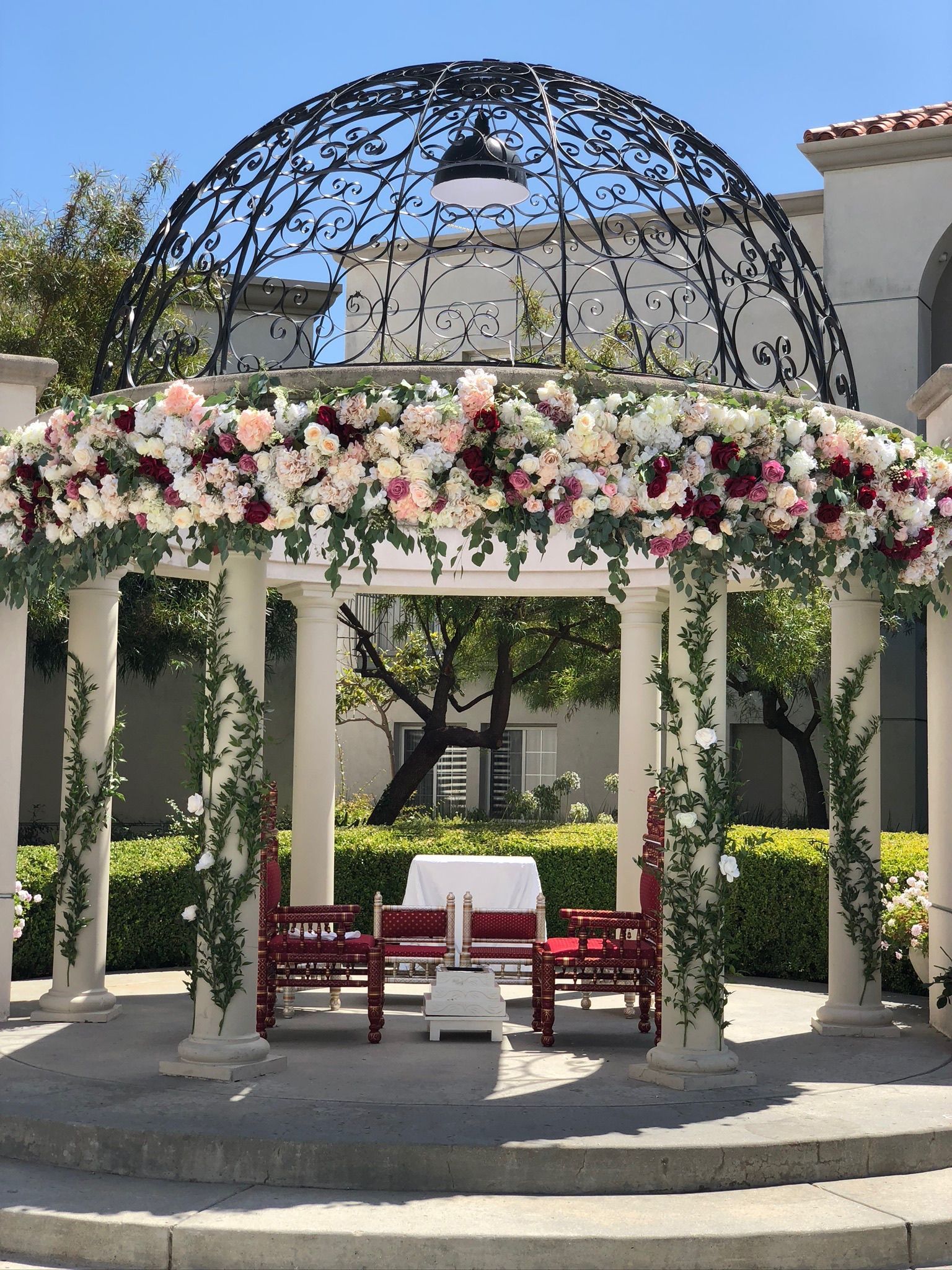 A gazebo decorated with flowers and chairs for a wedding ceremony.