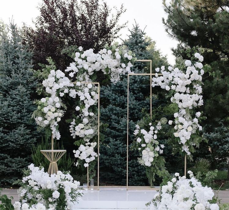 A wedding arch decorated with white flowers and greenery