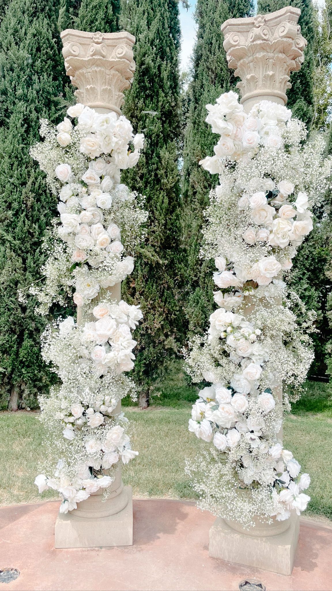 A couple of columns covered in white flowers and baby 's breath.