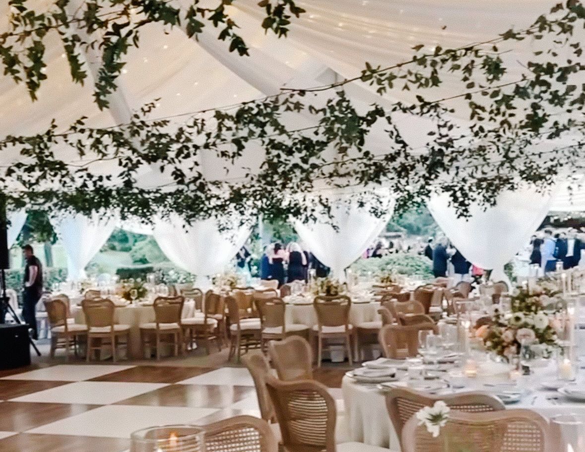 A large tent with tables and chairs set up for a wedding reception
