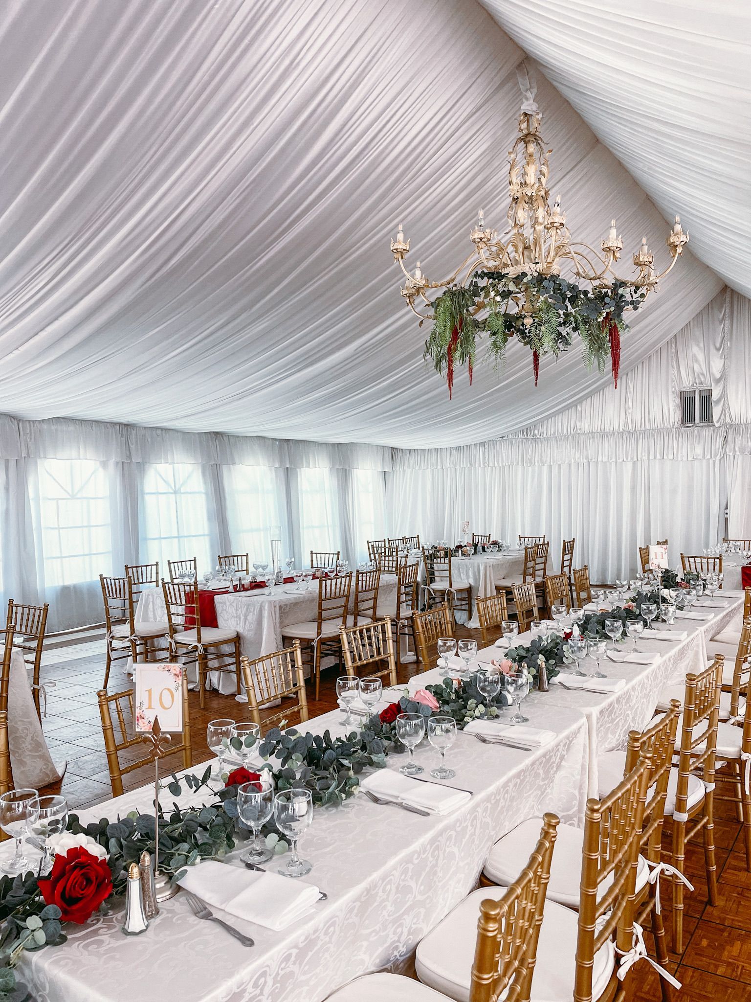 A long table with a chandelier hanging from the ceiling in a tent.