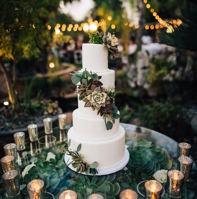 A wedding cake is on a table with candles and flowers