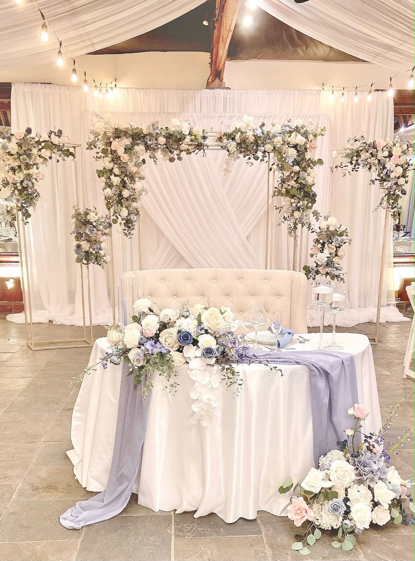 There is a table with flowers on it and a couch in the background.