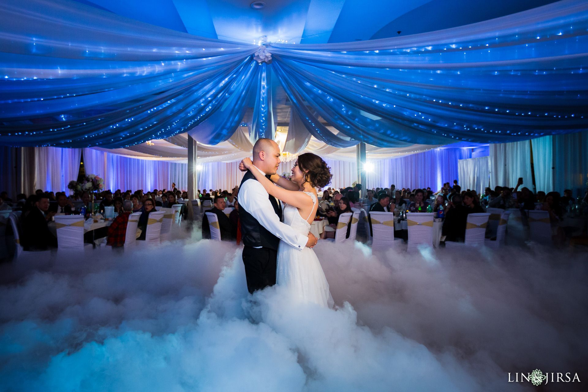 a bride and groom are dancing in a room filled with smoke .