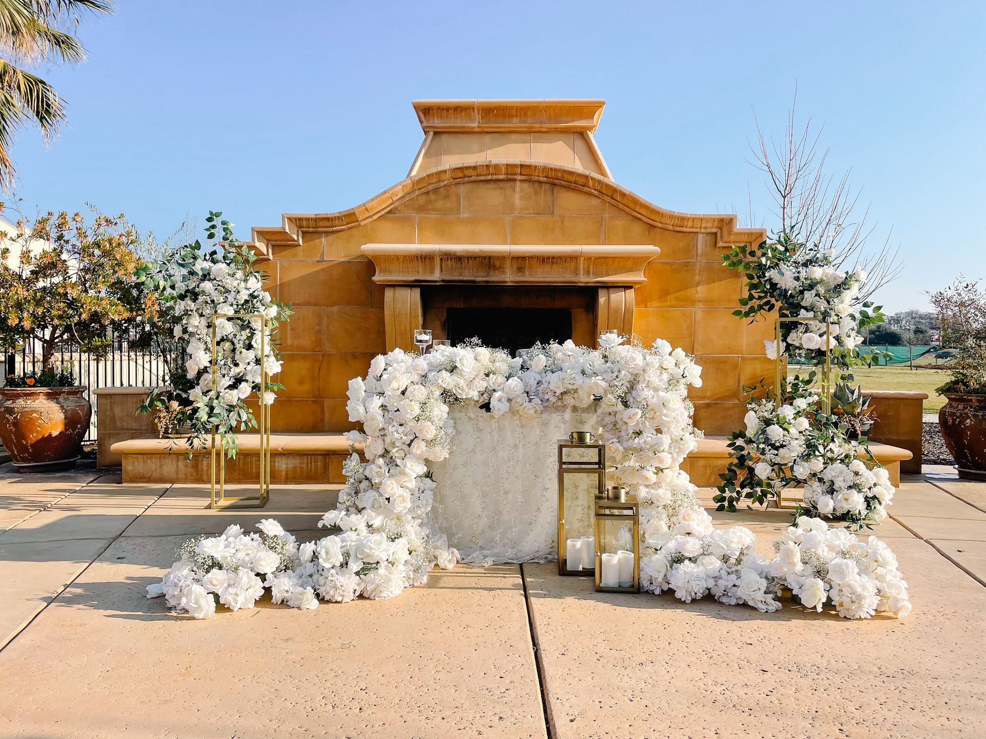 A table decorated with white flowers and candles in front of a building.