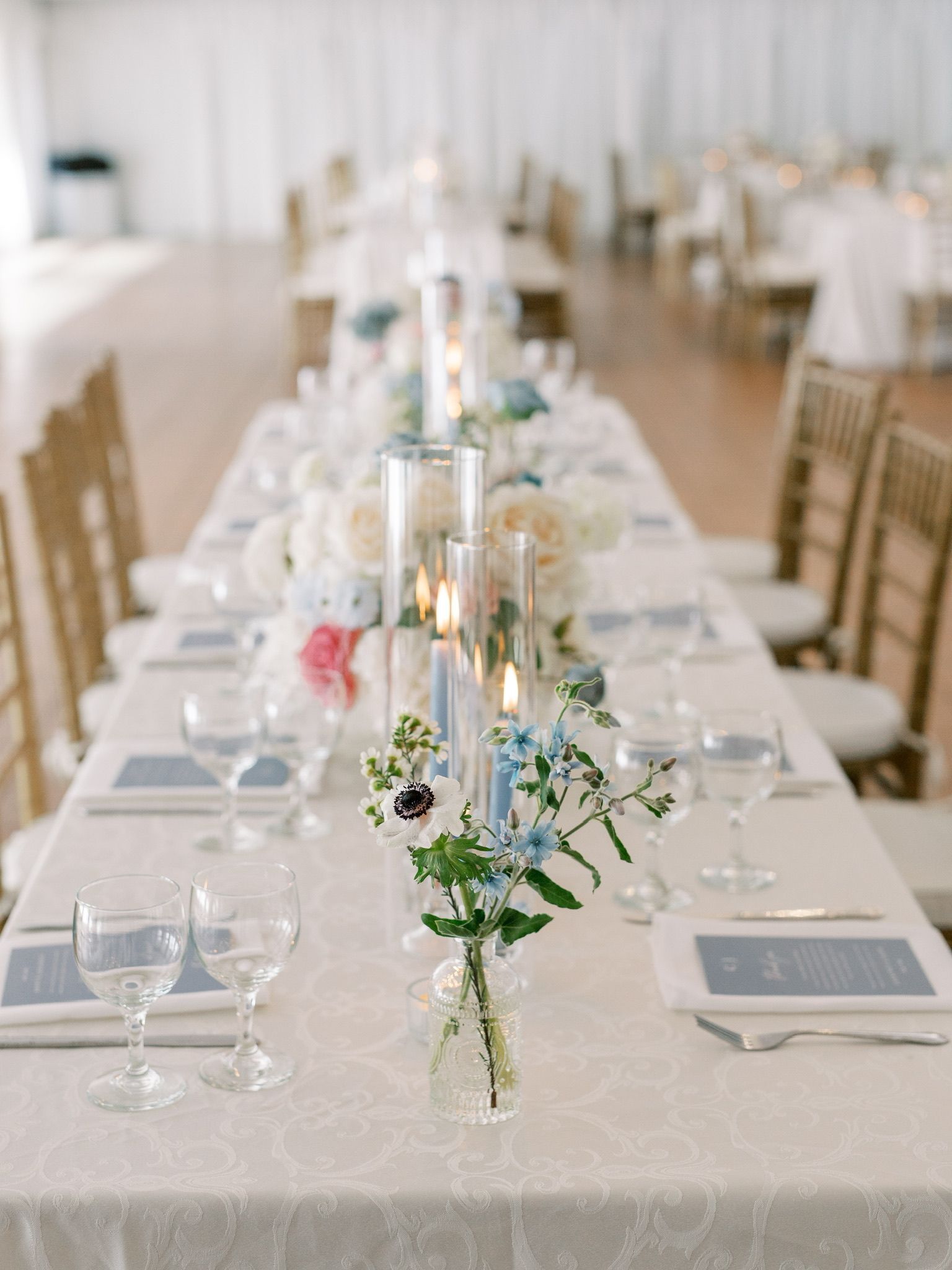 A long table with a vase of flowers and candles on it.