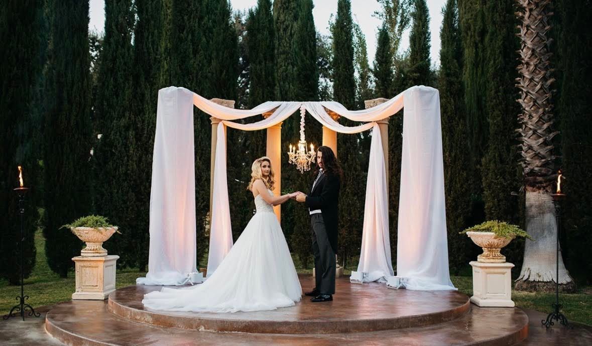 Couple Holding Hands in Front of A Wedding Backdrop Decoration