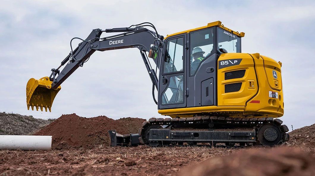 A yellow excavator is sitting on top of a dirt field.