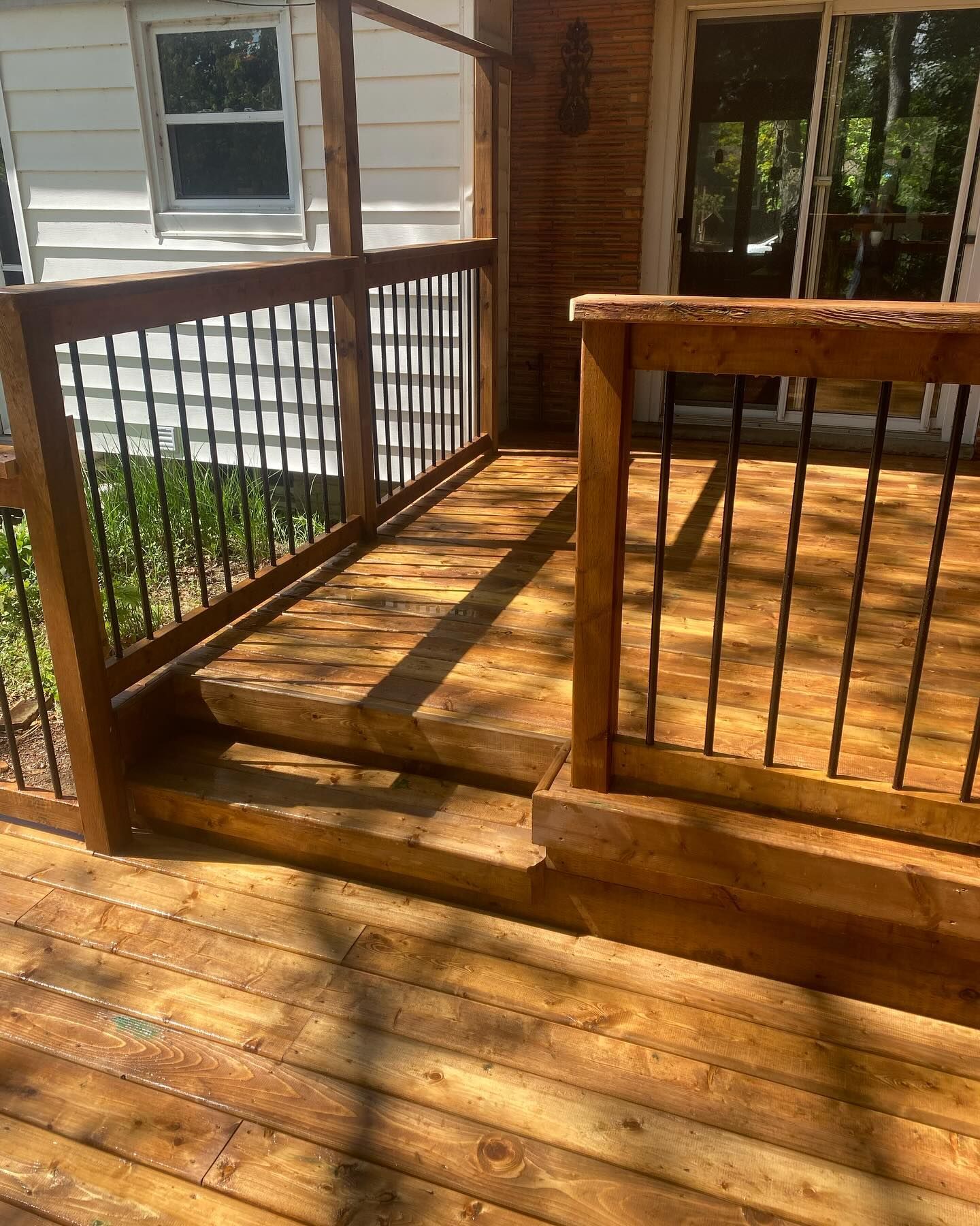 Wooden deck with railings and steps leading up to a doorway, outdoors.