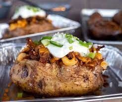 A baked potato filled with meat , cheese , sour cream and green onions.