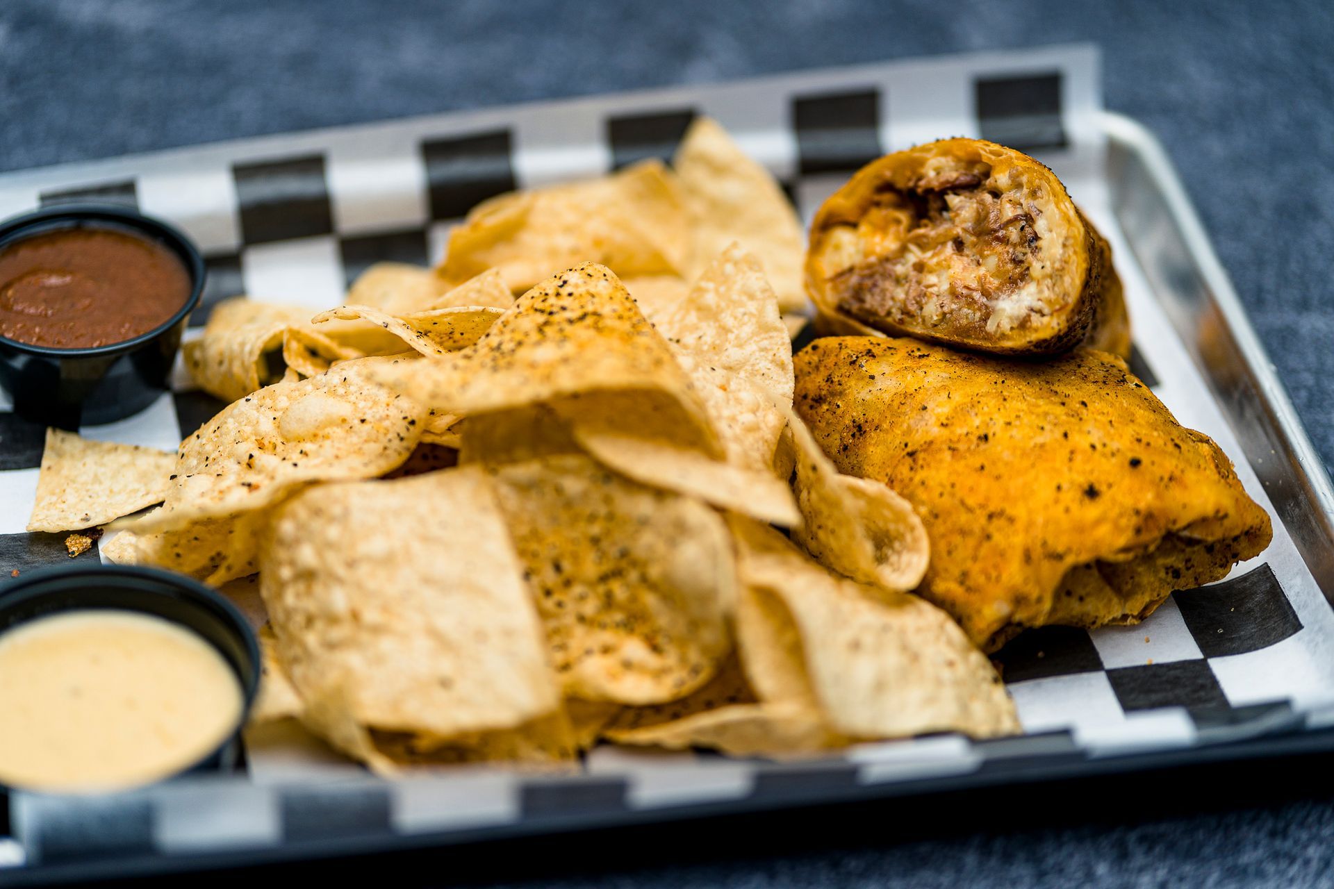A close up of a burrito and chips on a tray.