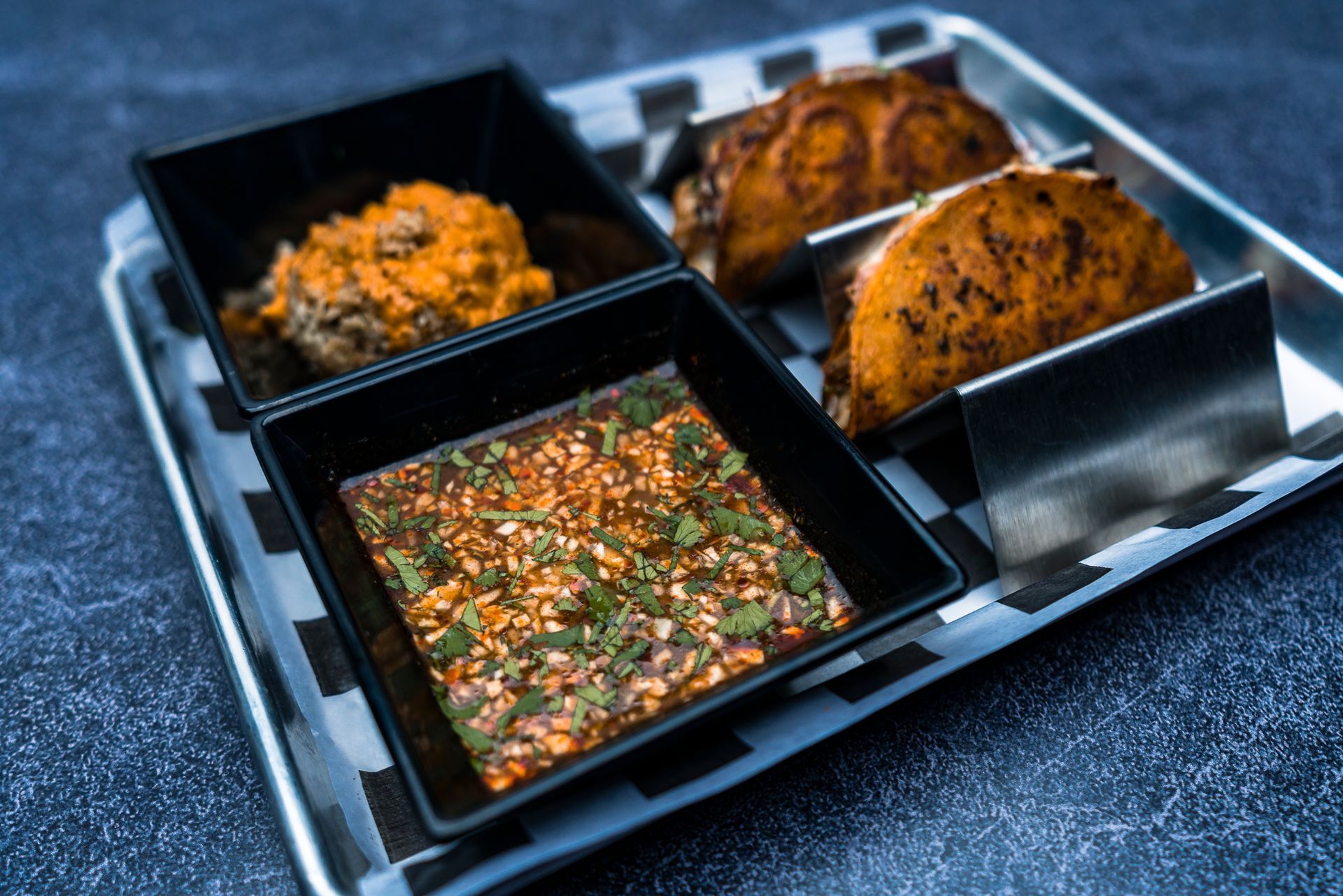 A tray of food with sauces and tacos on a table.