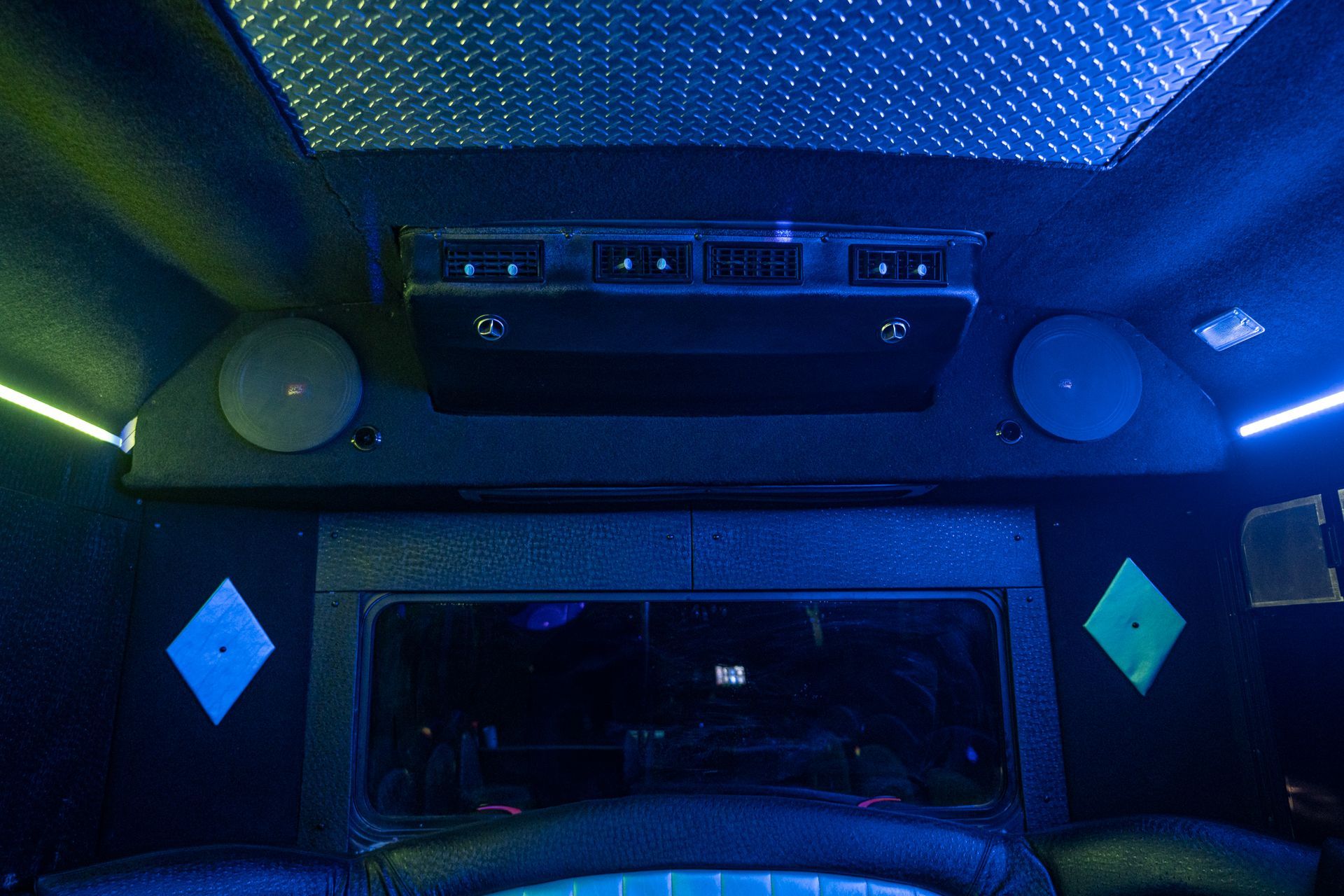 The inside of a limousine with blue lights and speakers.