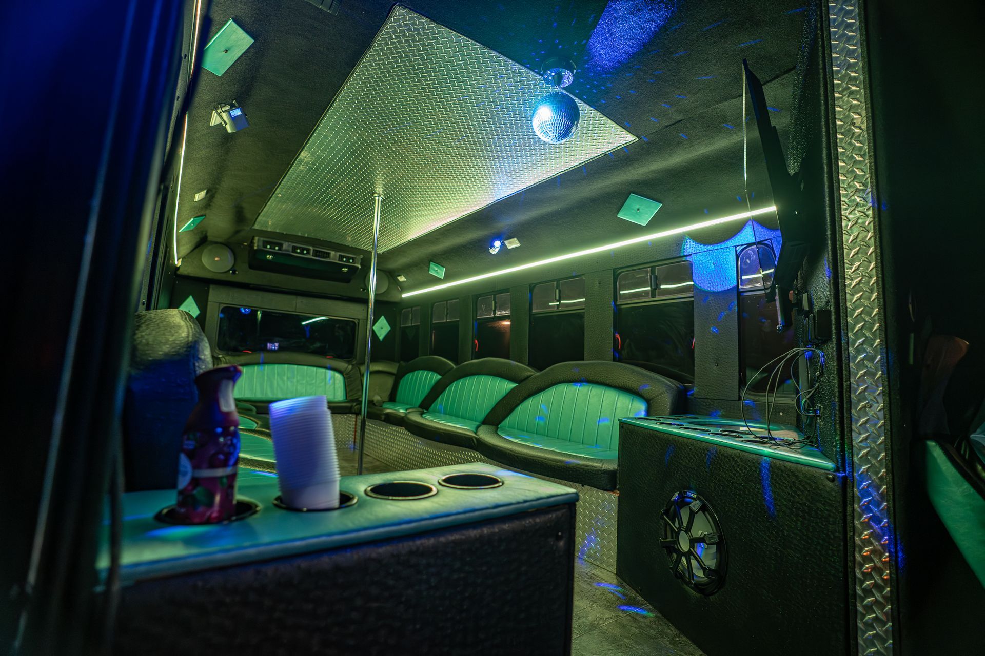 The inside of a limousine with green lights on the ceiling.
