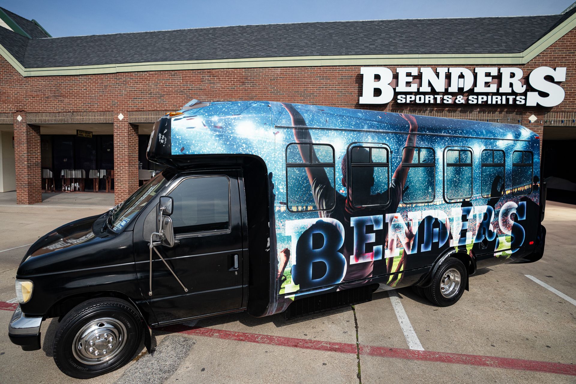 A black van is parked in front of benders sports & spirits