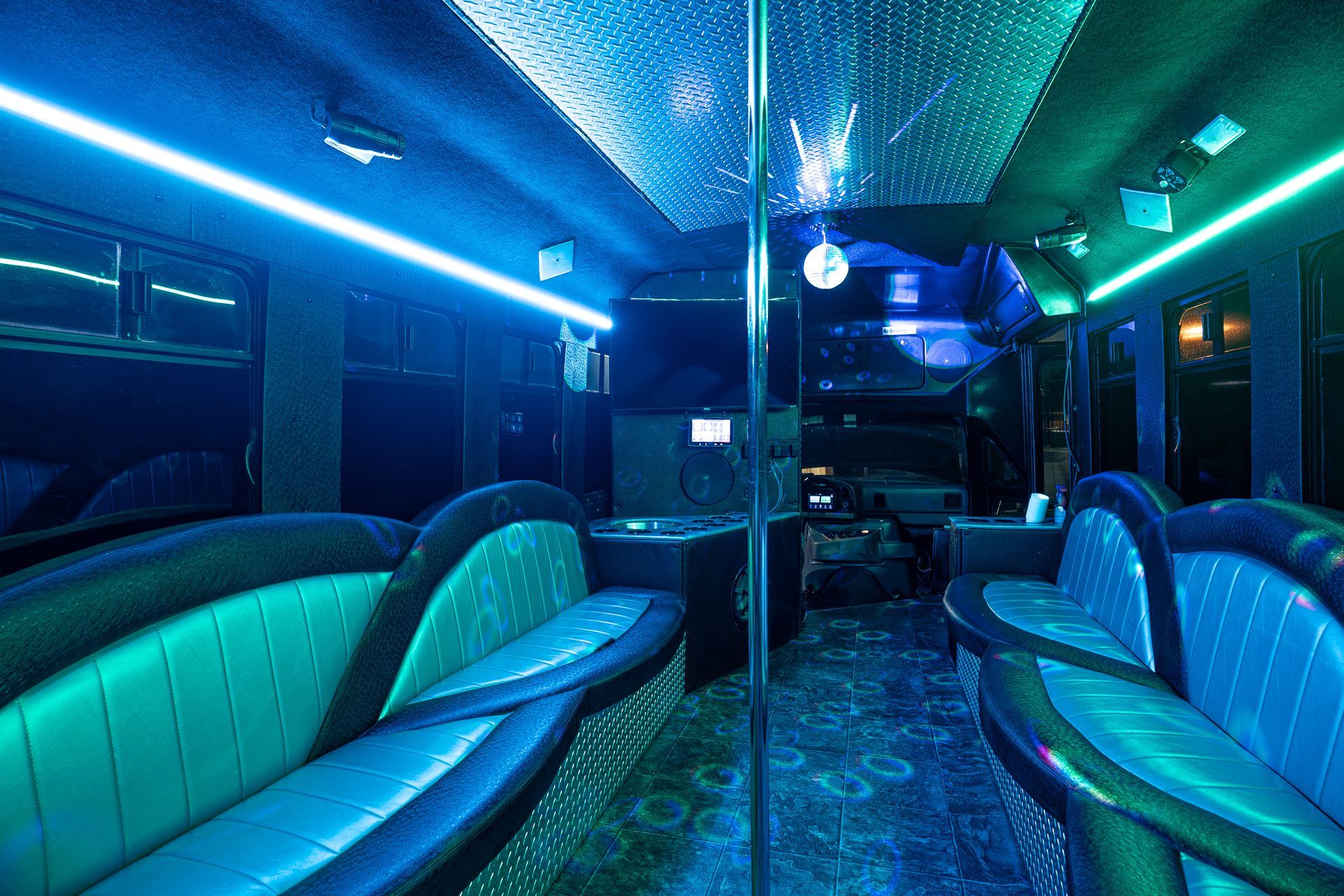 The inside of a party bus with blue lights on the ceiling.