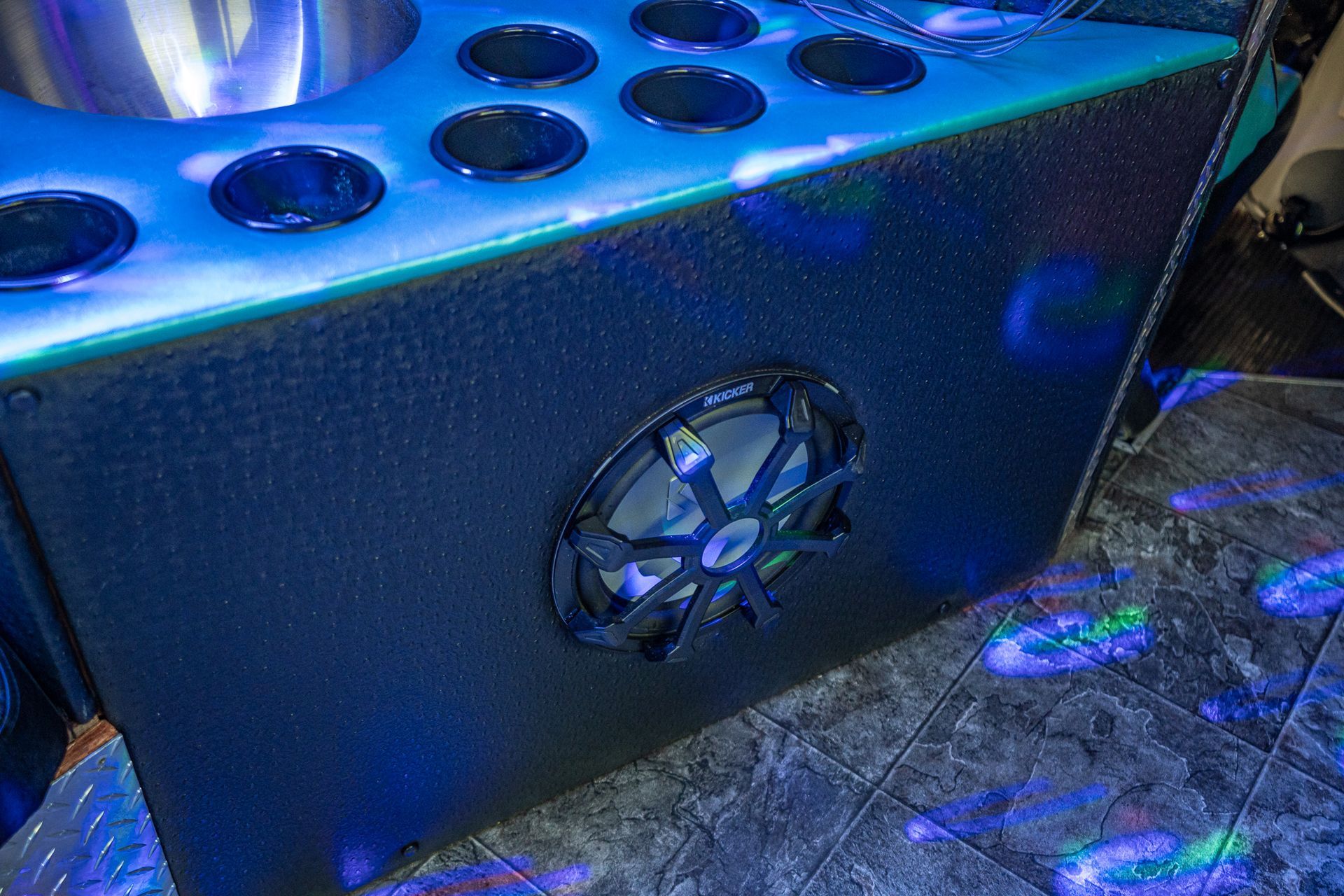 A blue speaker is sitting on a tiled floor in a room.