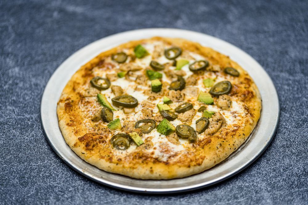 A pizza is sitting on a white plate on a table.
