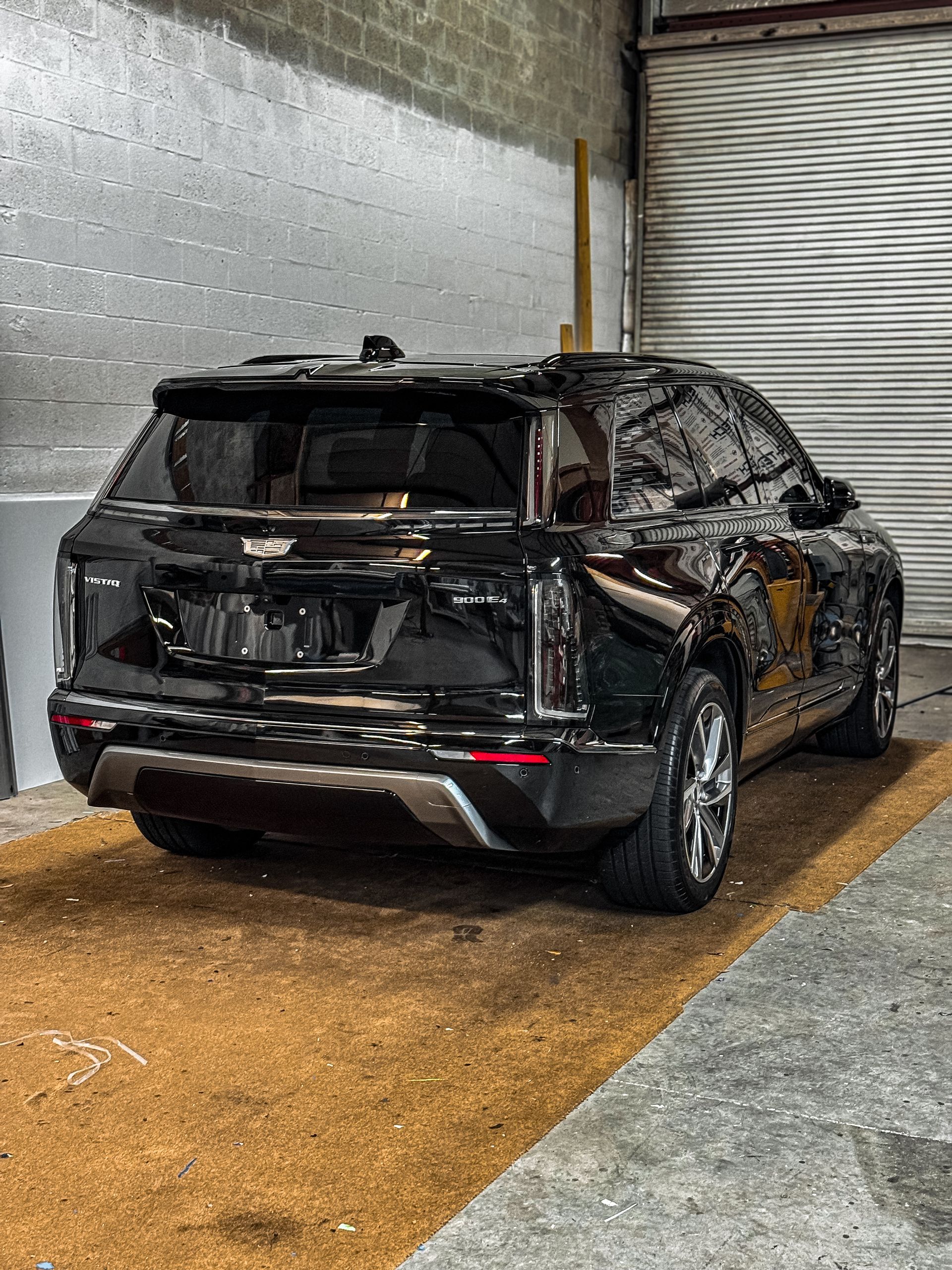 Black Cadillac SUV parked inside a garage, viewed from the rear.