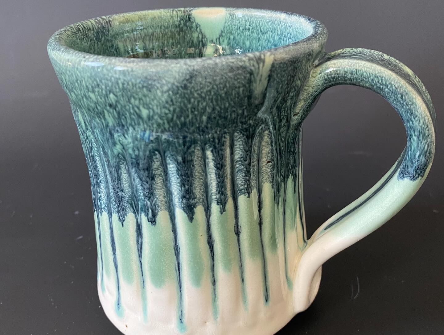 Ceramic mug with a dark green glaze that drips down over a light green and white base.
