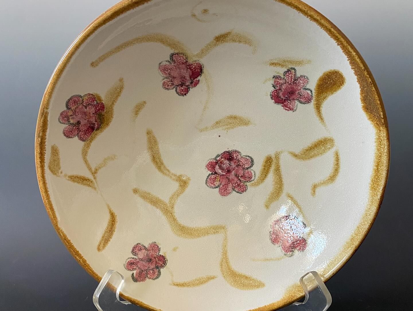 White ceramic bowl with pink flower designs and gold accents.