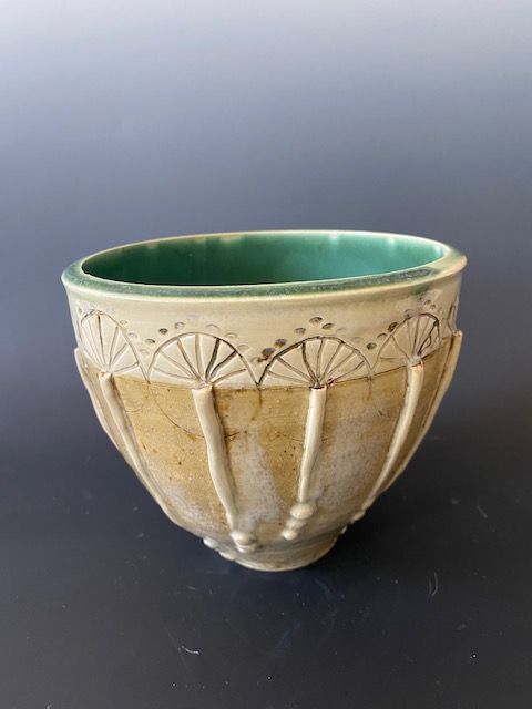 Ceramic bowl with green interior, tan exterior, and white decorative details.