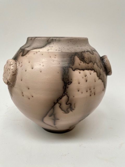 Rounded ceramic vase with rough handles and lightning-like black patterns on a pinkish-gray surface.