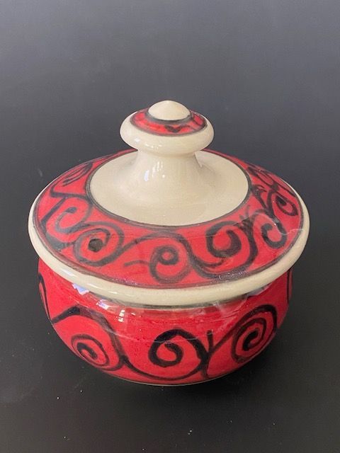 Red and cream ceramic trinket box with black swirl design.
