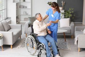 A nurse is helping an elderly woman in a wheelchair.