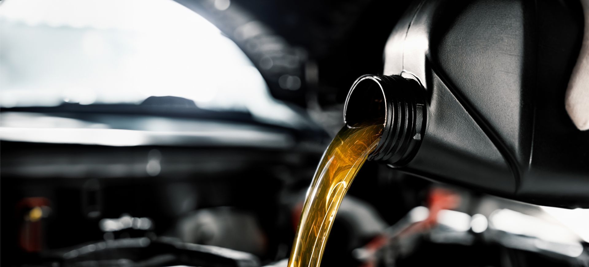 Motor oil pouring from a container into a car engine