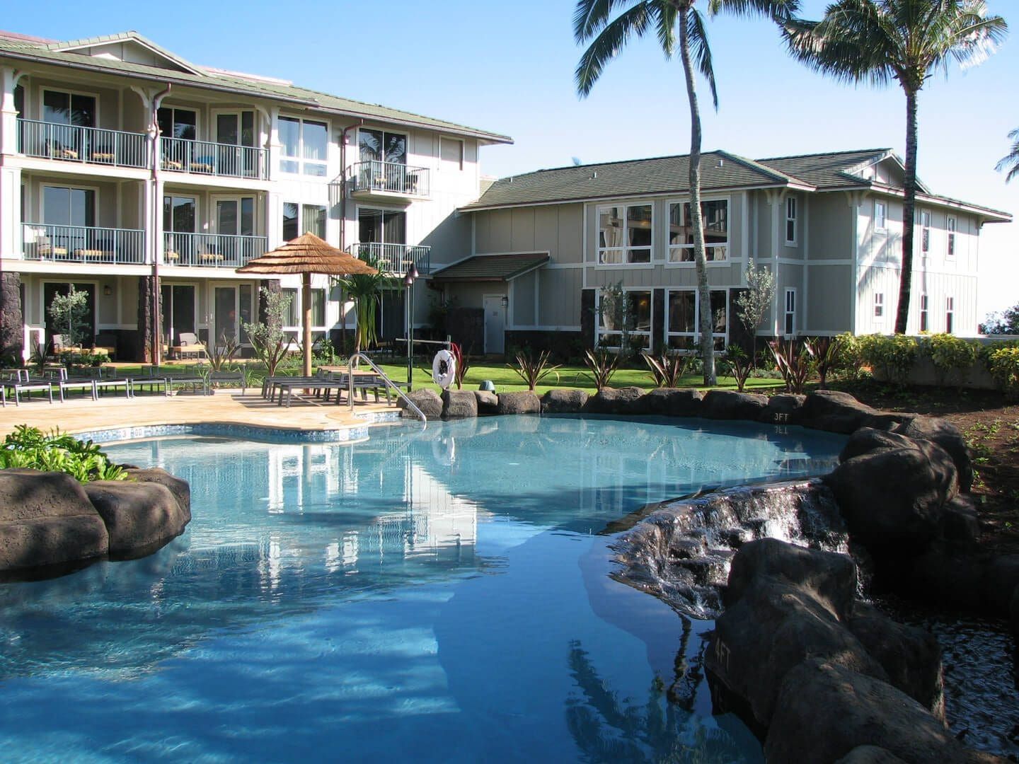 Pool with resort buildings and palm trees.