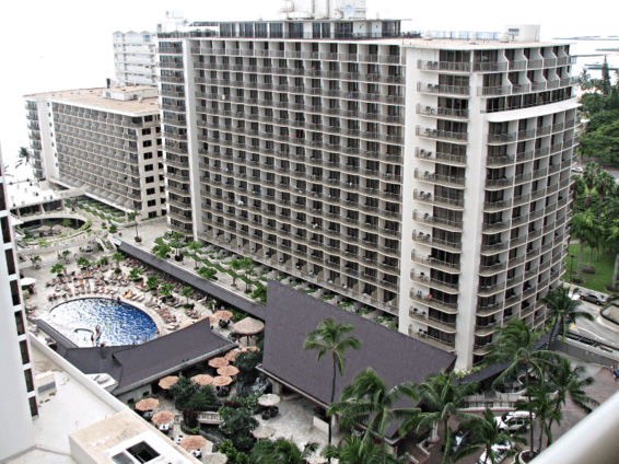 High-rise hotel buildings with a pool and palm trees in an outdoor setting.