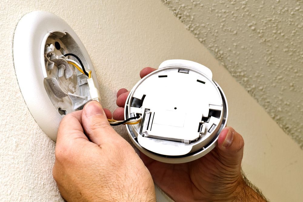 Smoke Alarm Being Repaired On Wall — Compliant Smoke Alarms in Townsville, QLD