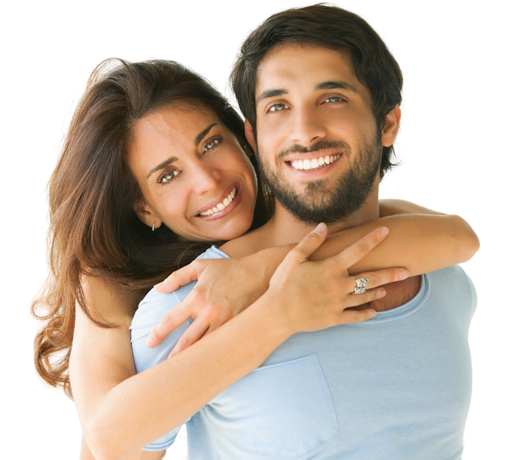 A woman with recently whitened teeth is hugging a man with a ring on her finger 