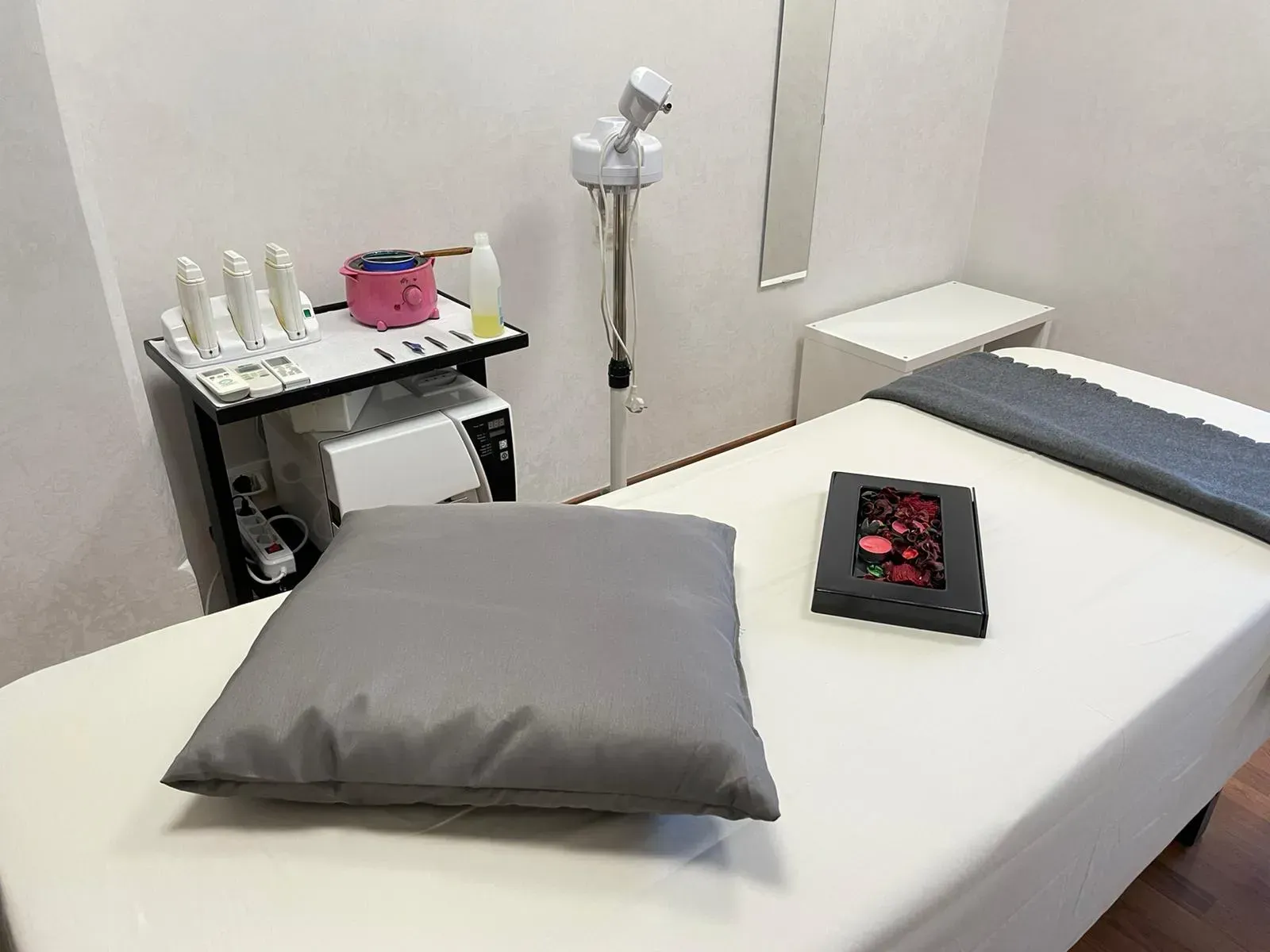 Sala per trattamenti spa con lettino per massaggi, attrezzatura e cuscino.