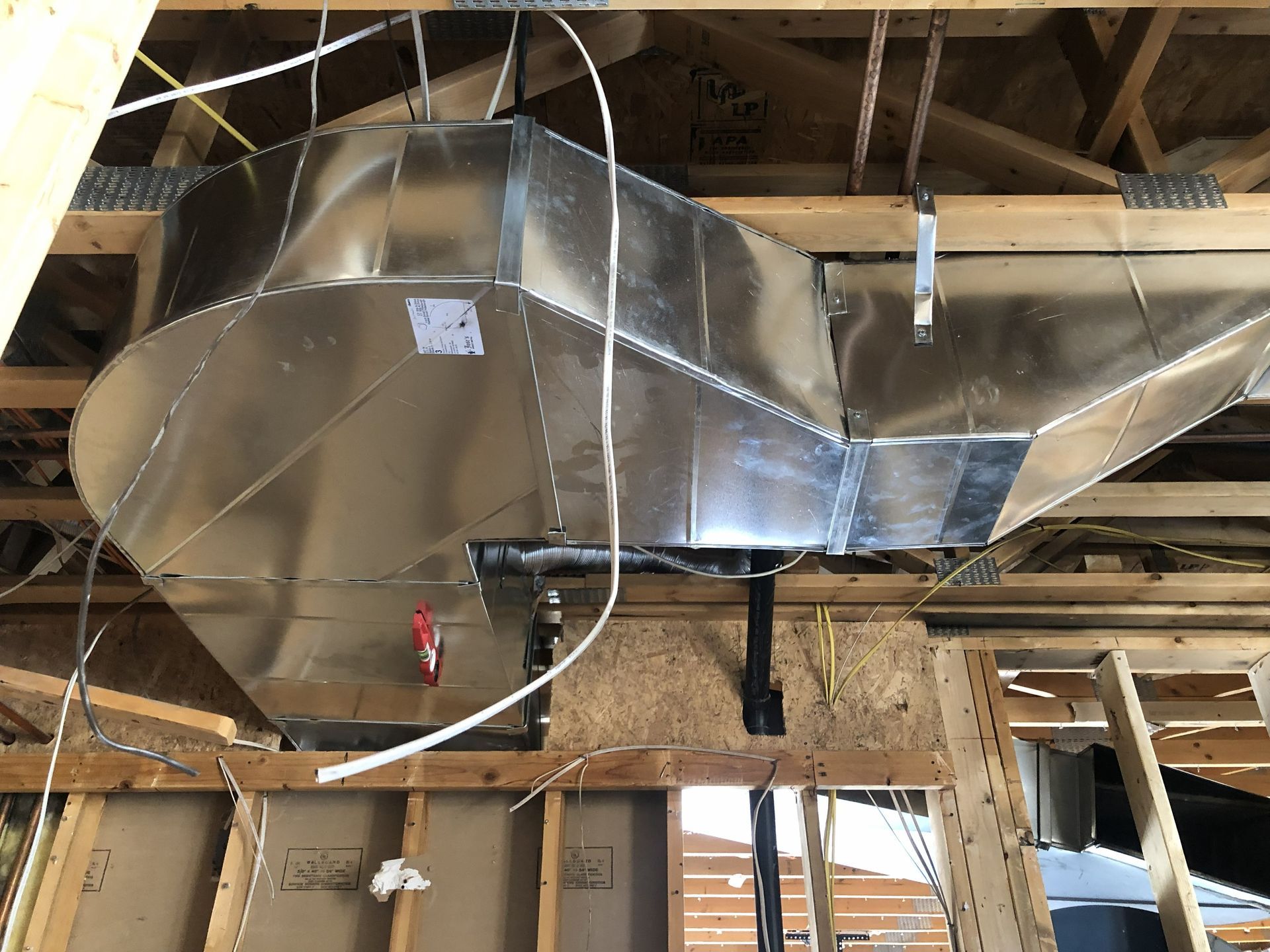 Galvanized metal HVAC ductwork installed in unfinished ceiling.