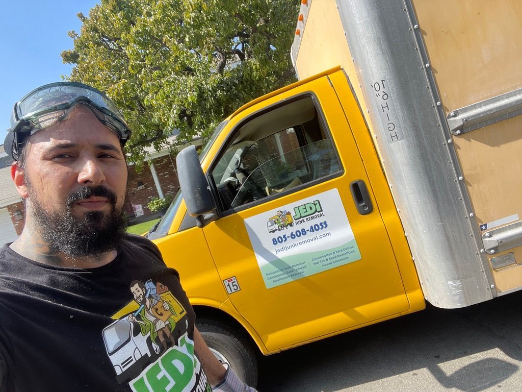 Man taking a selfie beside a yellow truck on a sunny street