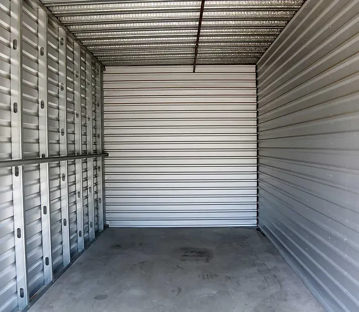 Empty metal storage unit with corrugated walls and a concrete floor