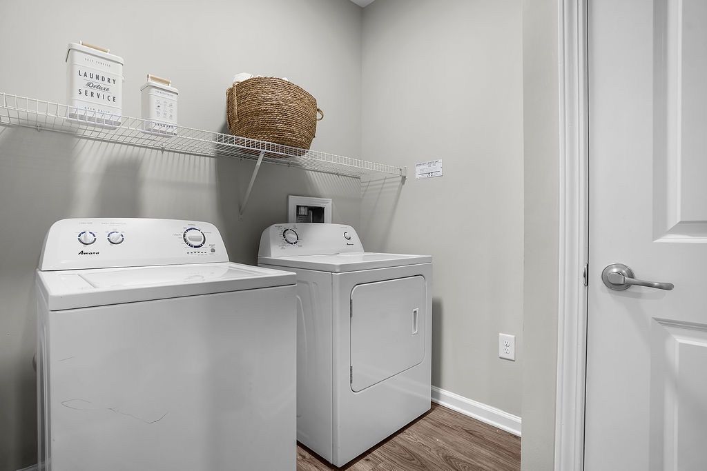 Laundry room with a washer and dryer, a wire shelf above, and a woven basket on the shelf.