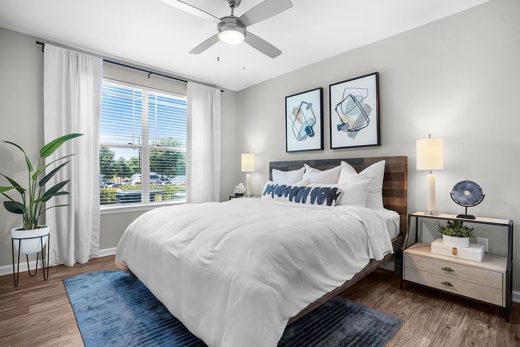 Bedroom with a large bed, white bedding, two nightstands, a ceiling fan, and a window with white curtains.