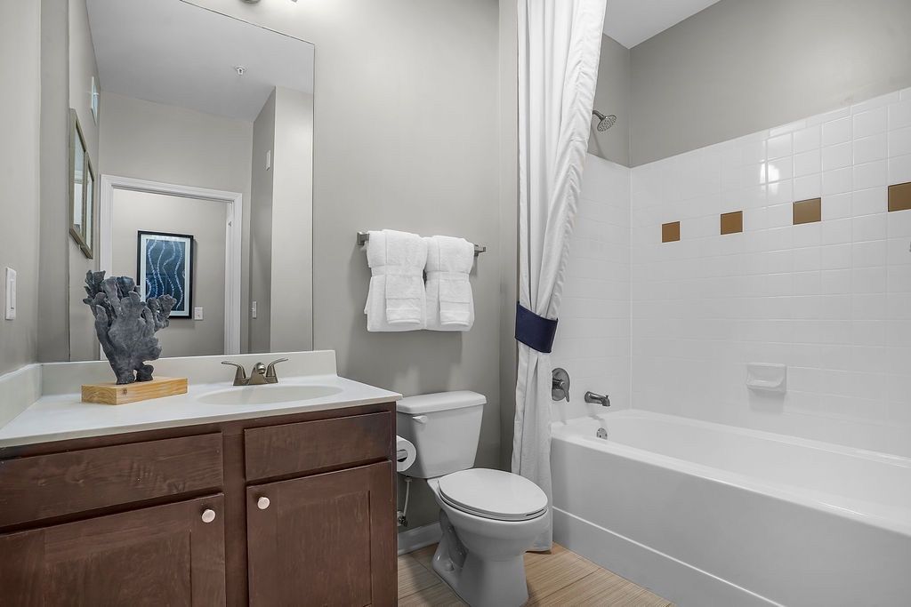Bathroom in an apartment unit with a vanity, mirror, toilet, and bathtub/shower.