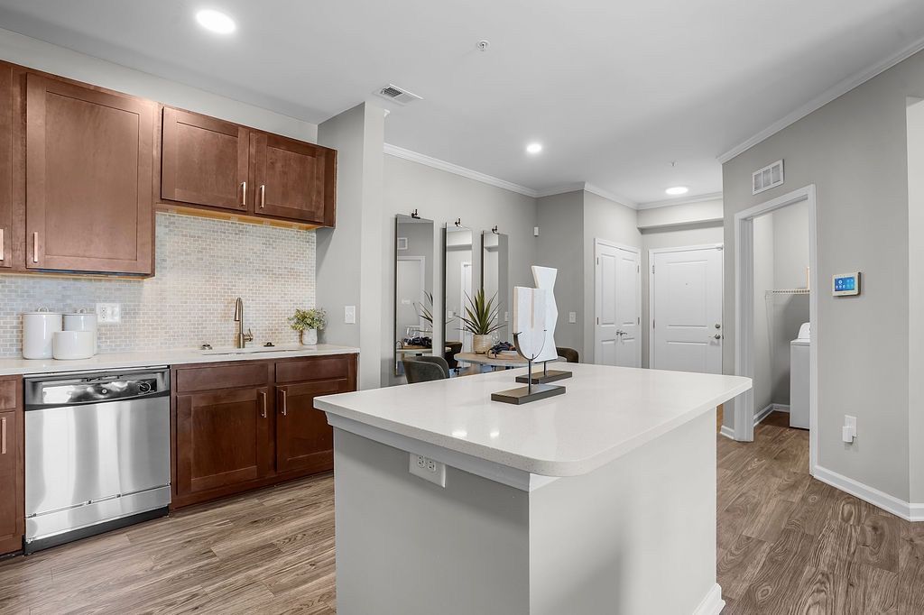 Bright, contemporary apartment kitchen with island and stainless appliances.