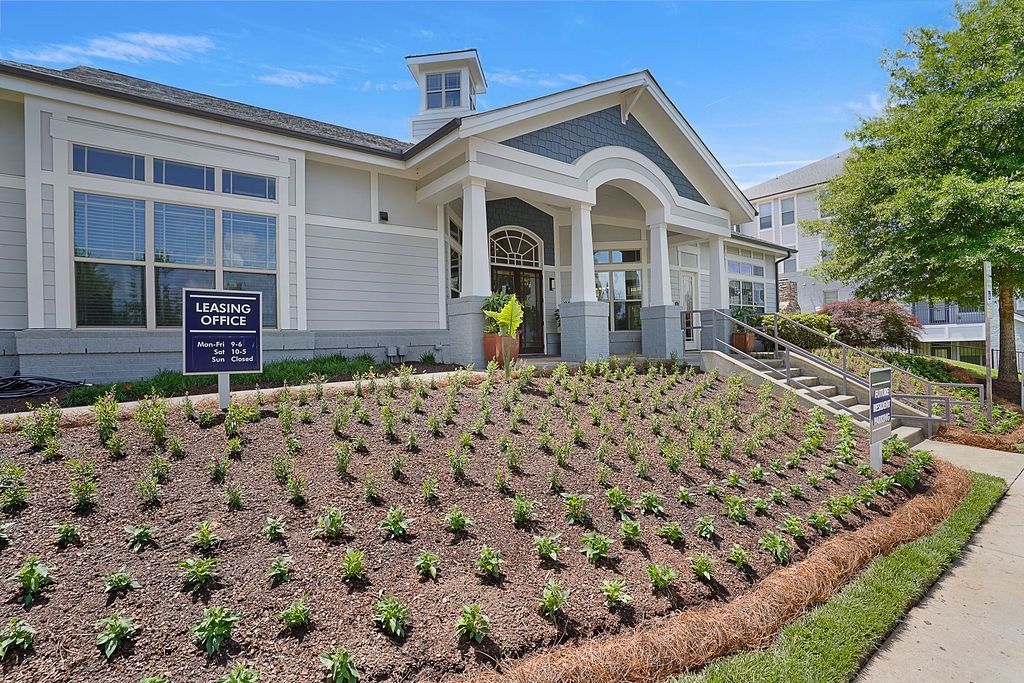 Exterior view of a leasing office building with a landscaped front slope and signage.