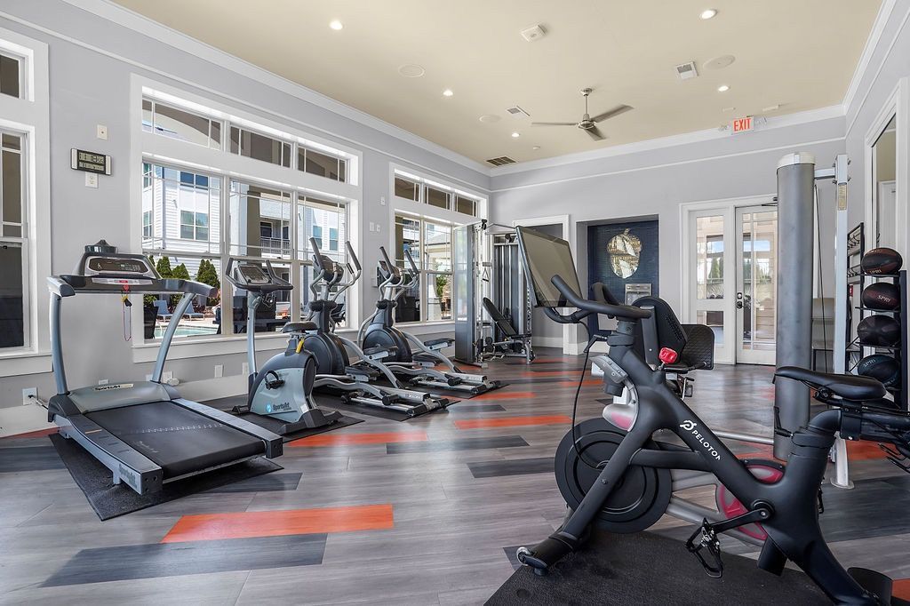 Bright community gym with treadmills, ellipticals, stationary bikes, and weights.